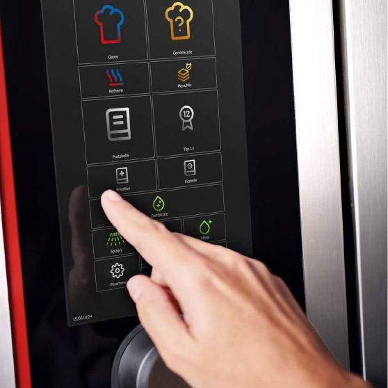 Primo piano di un dito che interagisce con un menu touchscreen con diverse icone funzionali come Cottura, CombiGuide, Retherm, MenuPlus, Registri, Impostazioni e Pulizia.