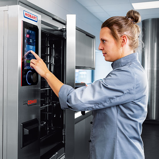 Una persona utilizza il display touchscreen di un apparecchio CHEF'S COMBI – con impostazioni di tempo e temperatura come “30” e “150°”, per un controllo preciso nelle cucine professionali.