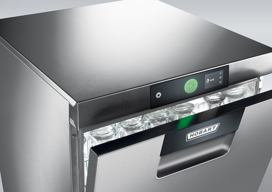 Lavastoviglie sottobanco HOBART in acciaio inox con sportello parzialmente aperto e bicchieri visibili all’interno, dotata di pannello di controllo digitale e pulsante verde di avvio.