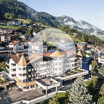 Veduta aerea del Gardena Grödnerhof a Ortisei in Val Gardena, un hotel cinque stelle Relais & Châteaux immerso nel paesaggio dolomitico, noto per il ristorante gourmet Anna Stuben premiato con una stella Michelin e alte valutazioni dalle principali guide.